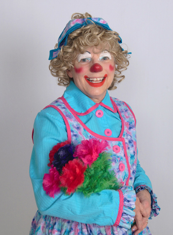 Rainbow the Clown poses, holding flowers