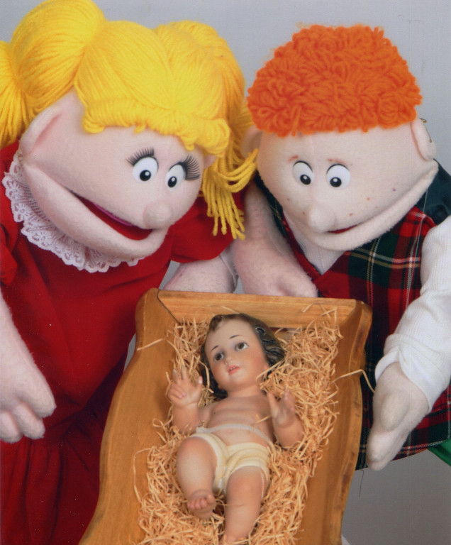 Two puppets look at Jesus in the manger